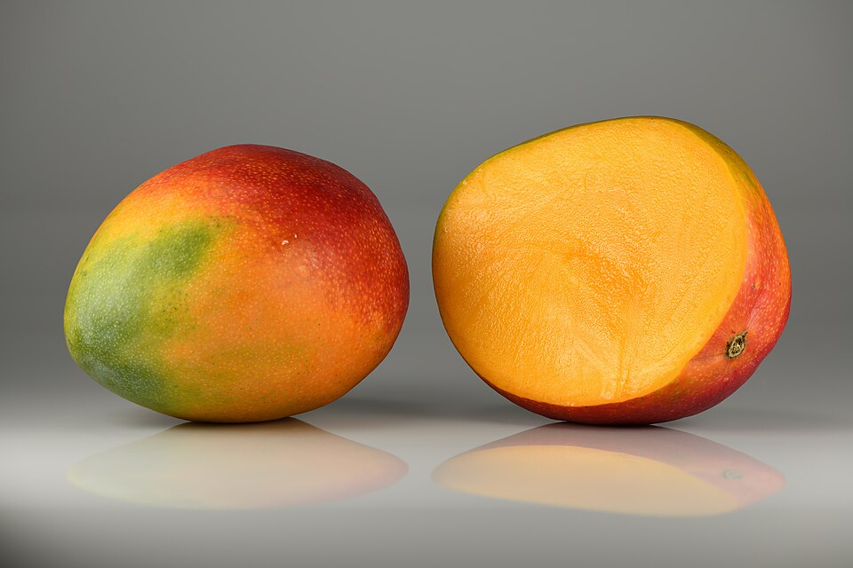 Fresh mangoes — whole and halved showing golden flesh